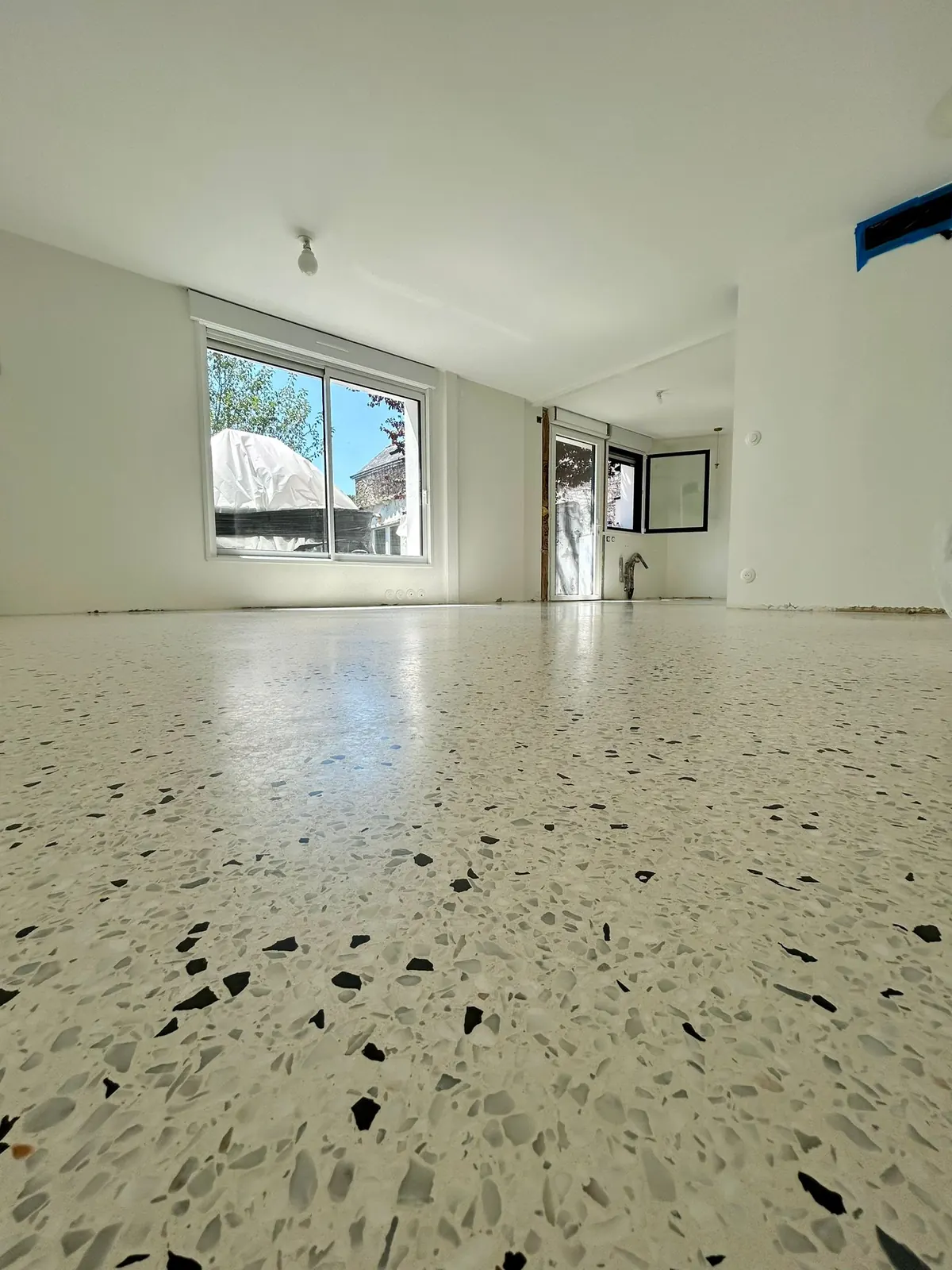 Sol en terrazzo blanc poli à éclats noirs dans un séjour lumineux
